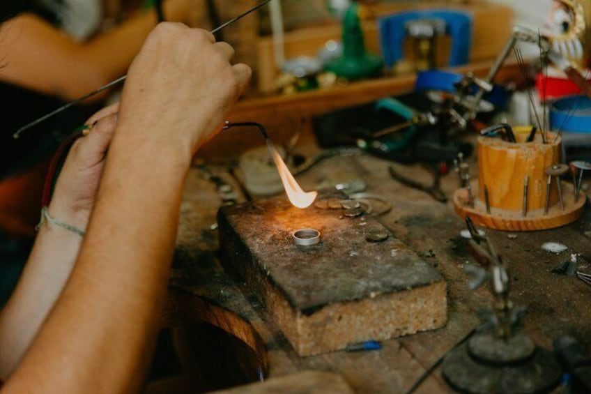 A person working with a torch on a metal object on a workbench. 1