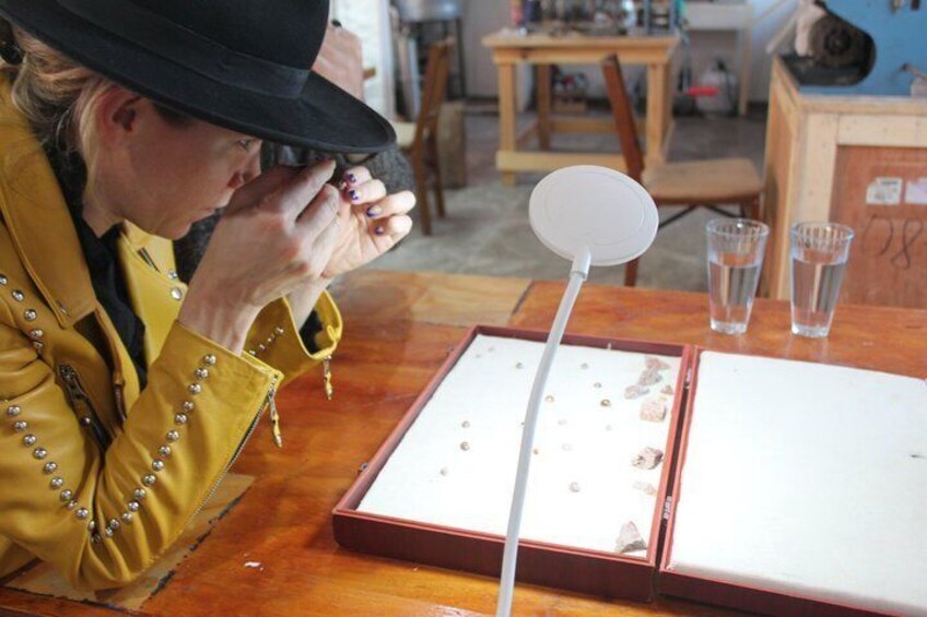 A person examining jewelry in a wooden box with a magnifying glass. 5
