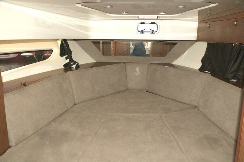 A boat interior with a curved seating area, a window, and a small overhead hatch. 4