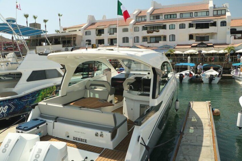 A marina with boats docked, a building with a flag, and a clear sky. 5