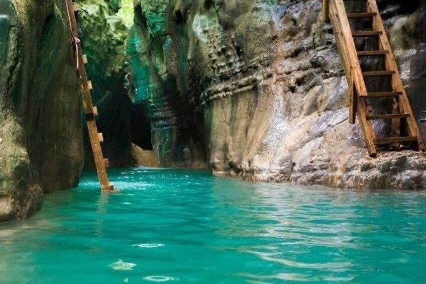 A natural pool with wooden ladders, surrounded by rocky walls. 3