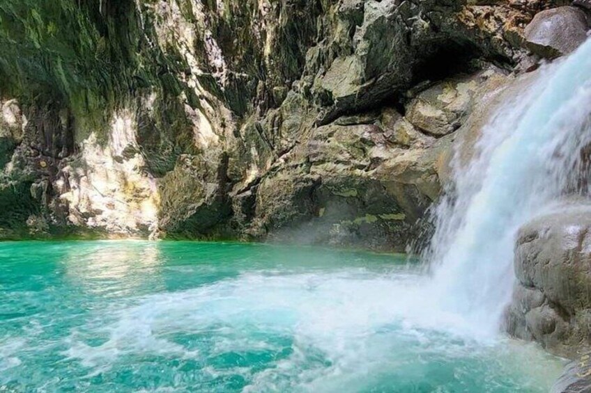 A turquoise pool with a waterfall. 4