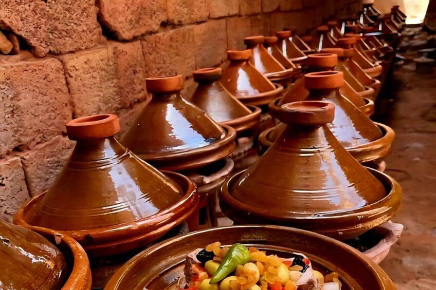 A row of traditional Moroccan tagines with clay lids, arranged against a brick wall. 2