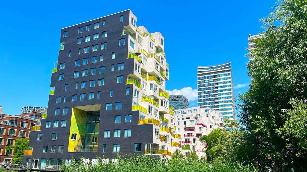 A modern urban building complex with multiple high-rise structures, surrounded by greenery and clear blue skies. 2