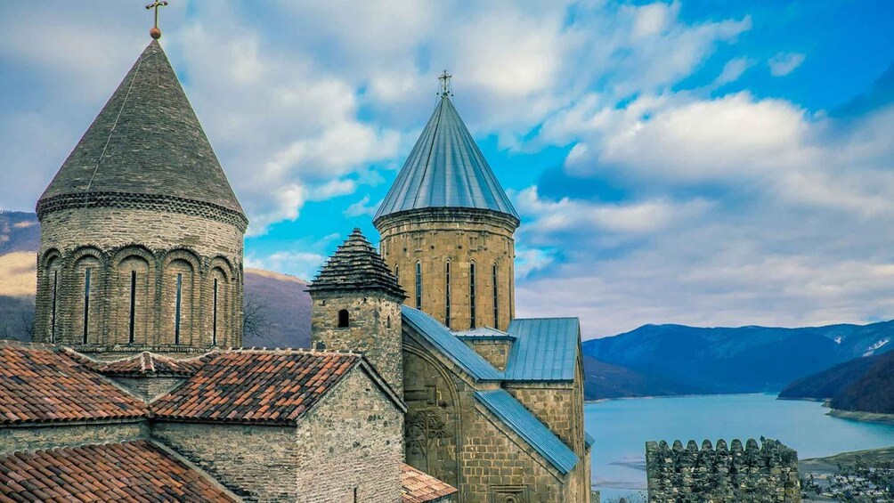 A church with two towers, a stone wall, and a lake in the background. 5