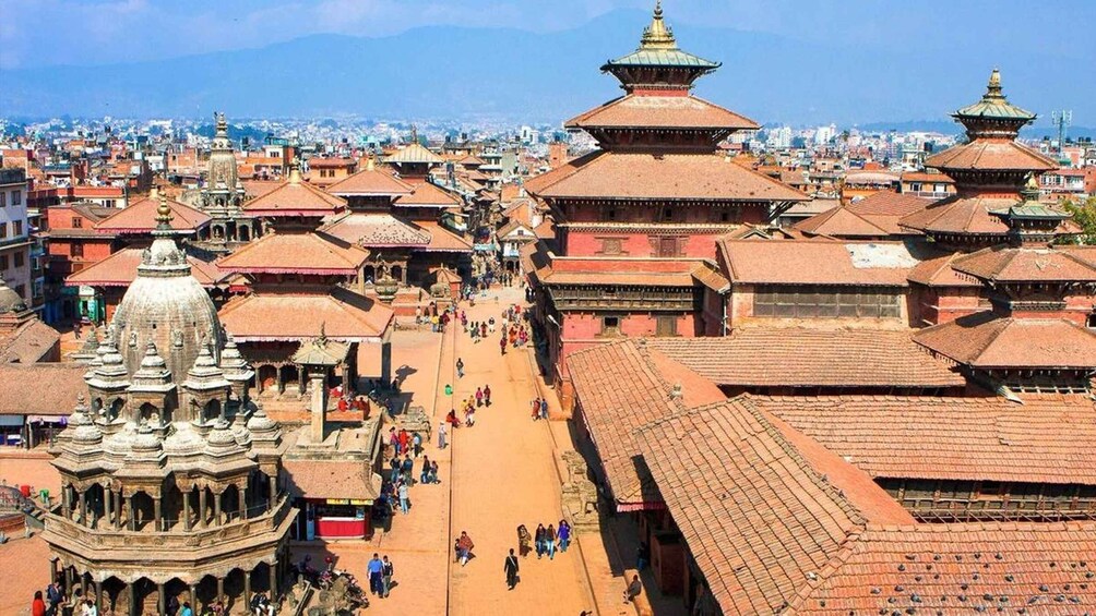 A historic cityscape with traditional architecture, including tiered temples and a prominent stupa. 3
