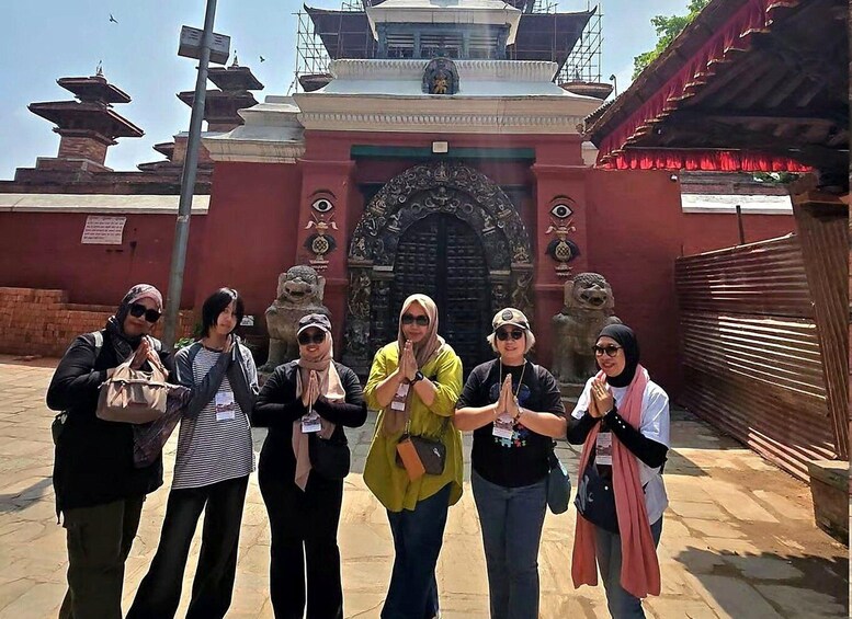 A group of people in front of a traditional gate with intricate carvings and a pagoda in the background. 2