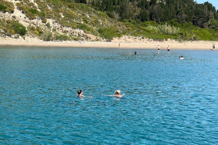 A calm sea with people swimming and walking on the beach. 5
