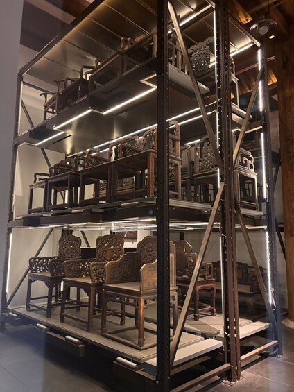 A metal shelving unit with ornate wooden chairs and tables. 5