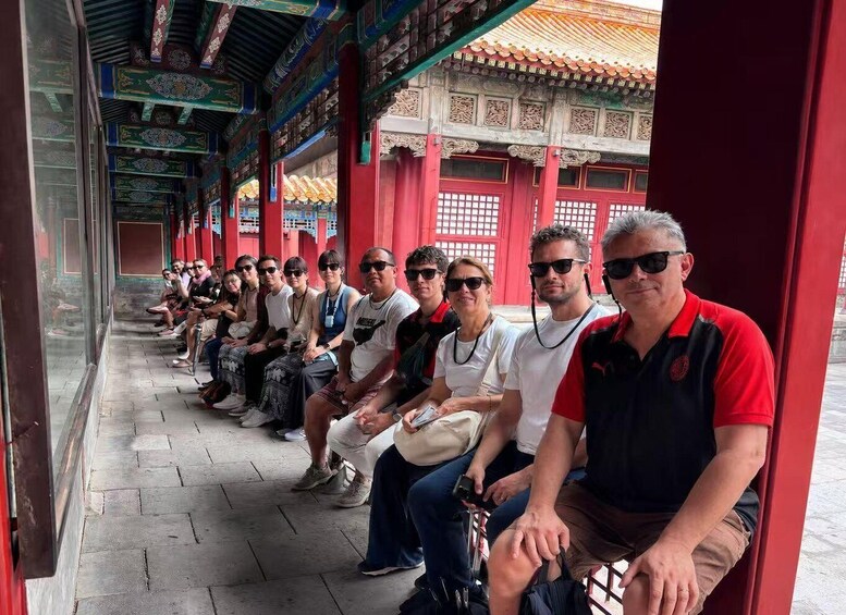 A group of people seated in a covered walkway with traditional architecture. 3