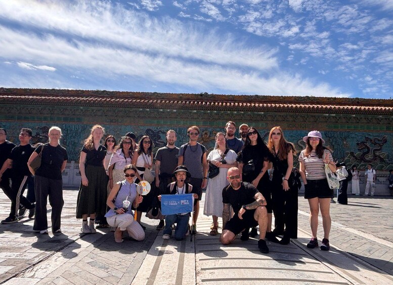 A group of people posing in front of a historic wall with intricate carvings. 5