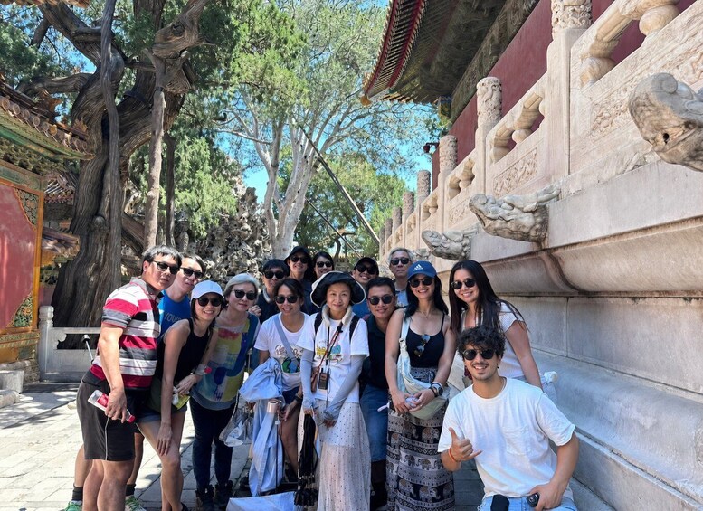 A group of people posing in front of a temple with intricate stone carvings and a traditional roof structure. 4