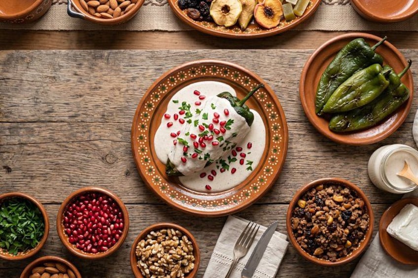 A wooden table with various bowls containing nuts, dried fruits, and a central plate with a food item garnished with pomegranate seeds. 1