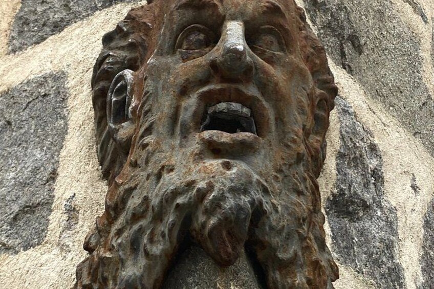 A weathered stone carving with a lion's head, rough texture, and visible wear. 2