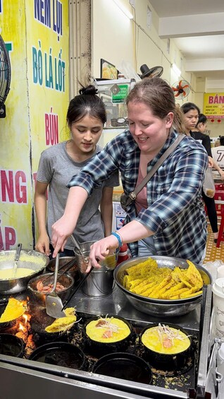 Two people cooking at a street food stall with various dishes being prepared. 4