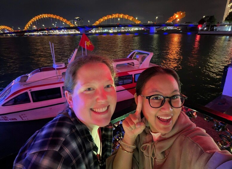 A boat docked near a brightly lit bridge at night. 2