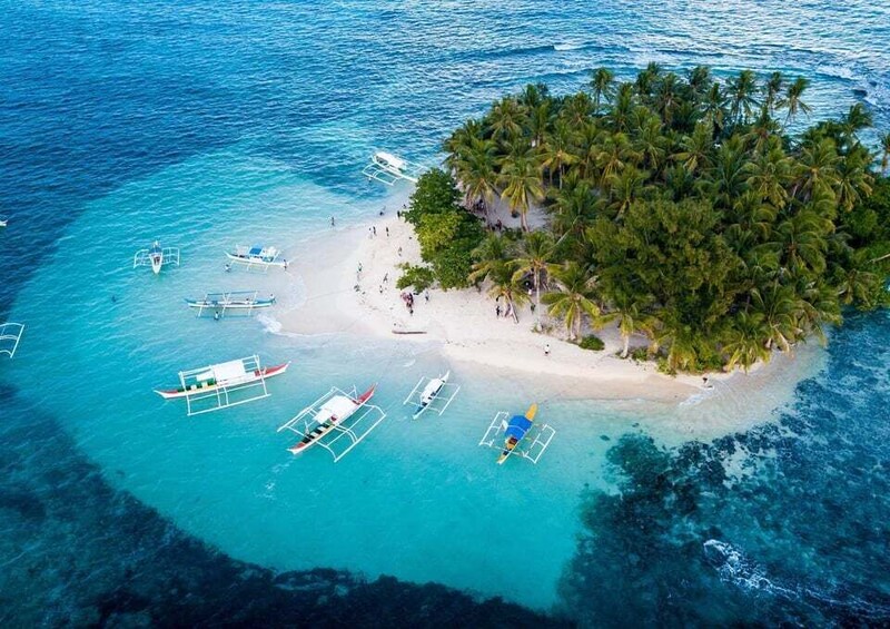 A tropical island with a beach, palm trees, and several boats anchored in the water. 3