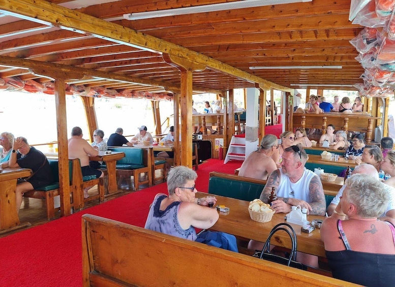 A wooden outdoor café with red carpeted seating and patrons enjoying their meals. 4