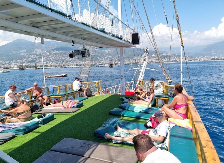 People relaxing on a boat deck with artificial grass seating and a cityscape in the background. 5