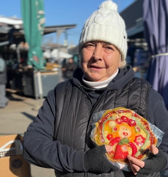A person holding a pizza with various toppings. 3