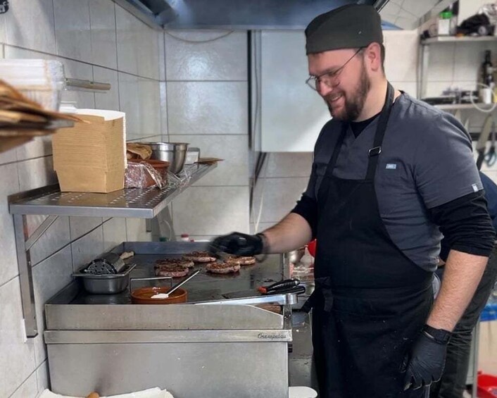 A chef cooking burgers on a grill in a kitchen. 4