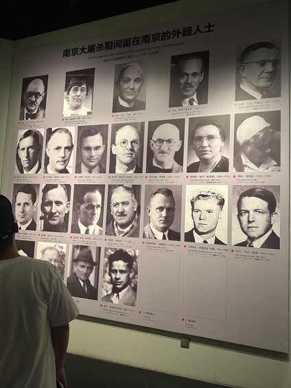 A wall displaying numerous black and white photographs of individuals with their names and dates of birth. 2