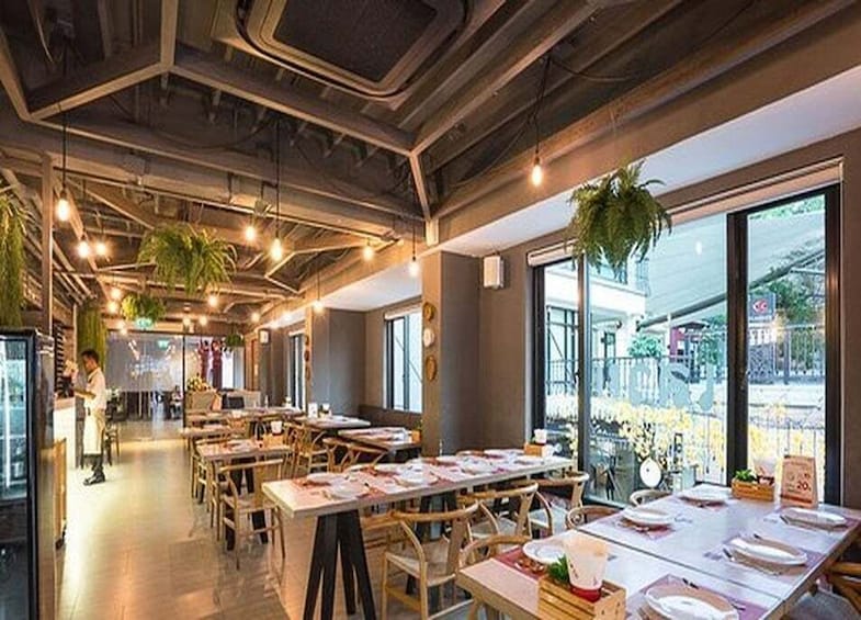 An indoor restaurant with wooden tables, hanging plants, and large windows. 5