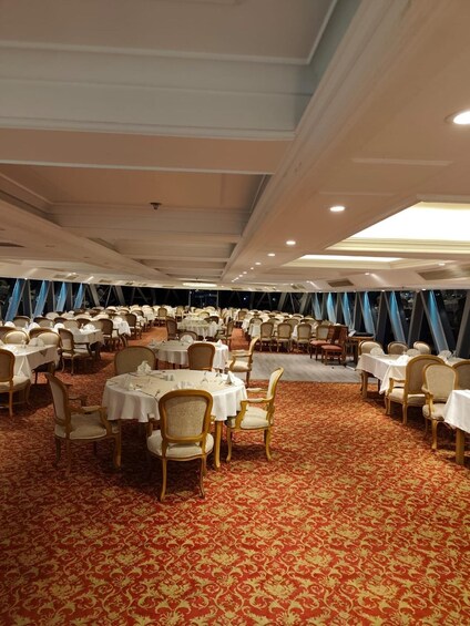 A banquet hall with round tables, chairs, and a red carpet. 5