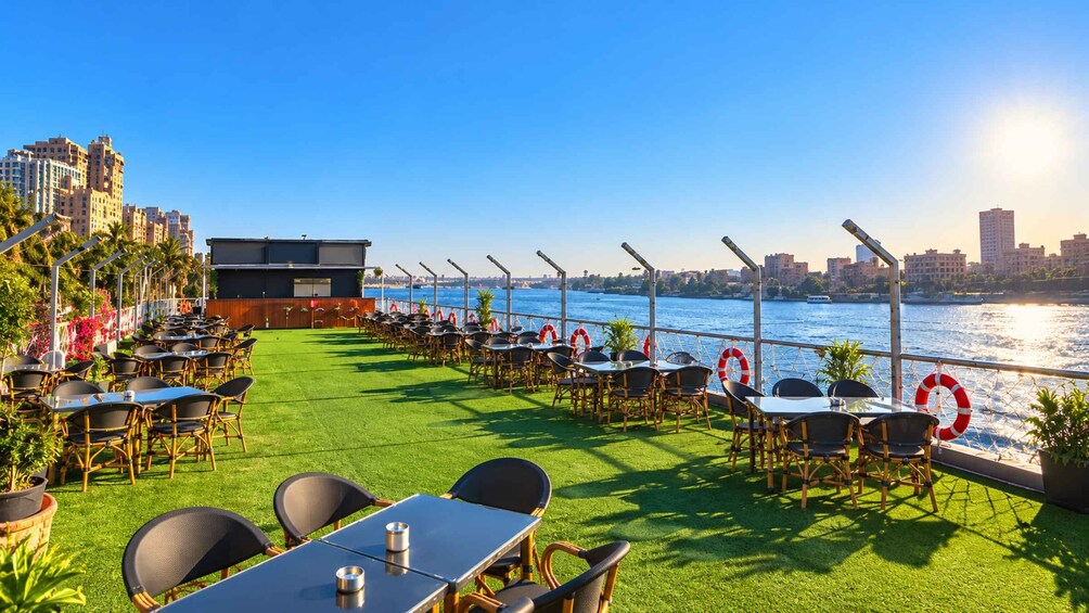 Une terrasse sur le toit, dotée de tables et de chaises, offrant une vue sur le paysage urbain qui s’étend le long du littoral. 2