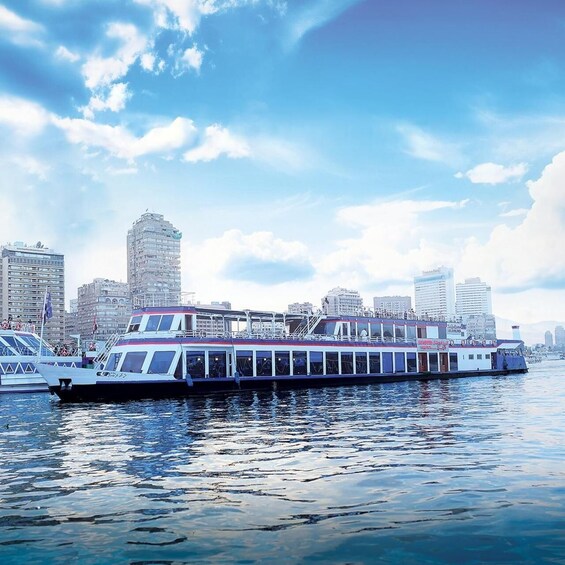A river cruise ship docked at a pier with a city skyline in the background. 1