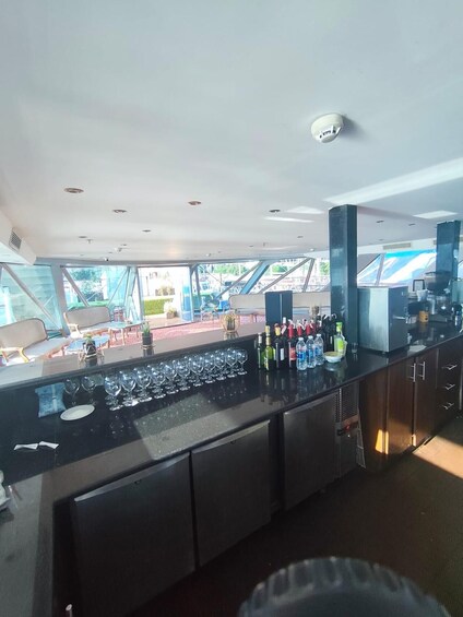 A modern bar area with a glass top counter, wine glasses, and bottles. 4