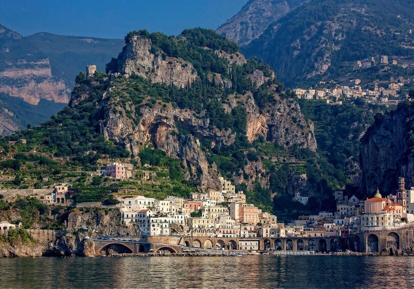 A coastal town with buildings on a hillside, a bridge, and a castle on a cliff. 2