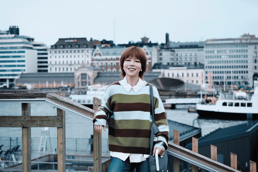 A person standing on a wooden deck with a cityscape in the background. 5