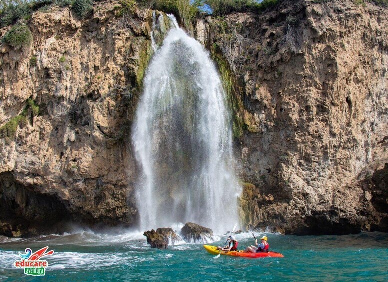 A waterfall in a rocky landscape with kayakers. 1