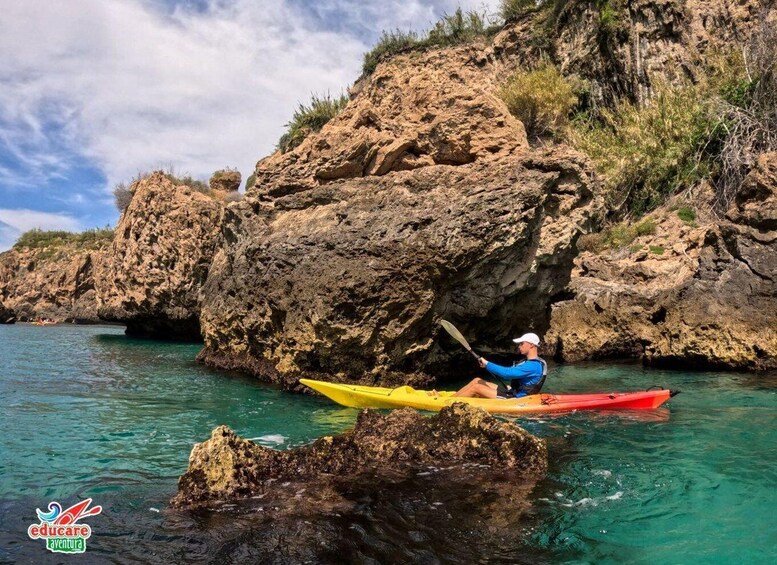 A person kayaking in clear waters near rocky cliffs. 5