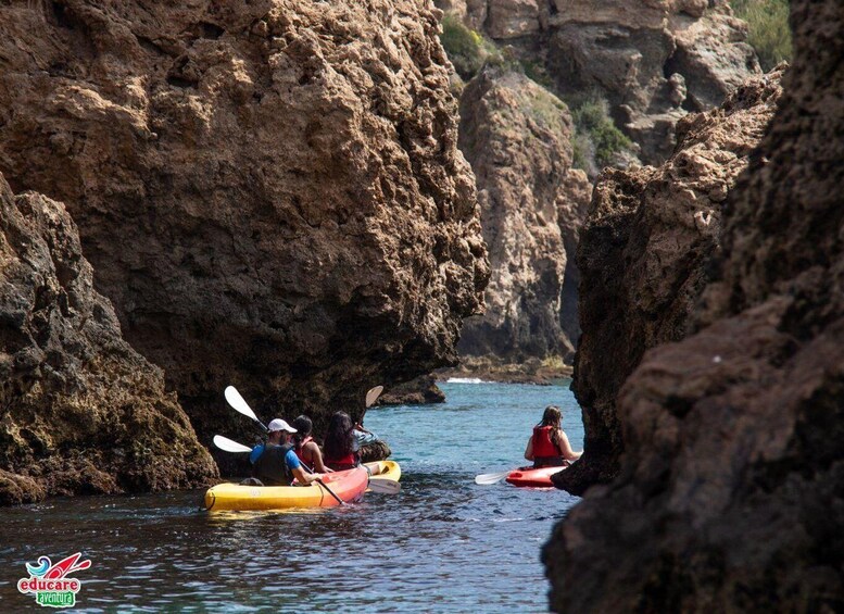 People kayaking in a narrow waterway between rocky cliffs. 4