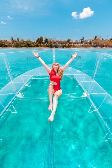 A person in a red swimsuit floating on a transparent pool with clear blue water. 5