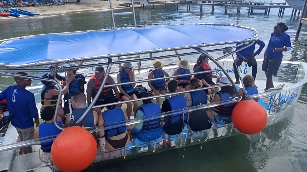 A boat with people wearing life jackets, a blue canopy, and orange buoys. 3