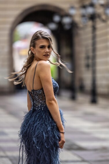 A person in a blue feathered dress walking on a city street. 2