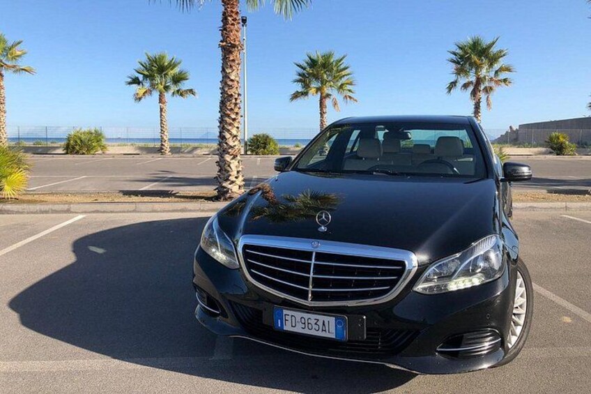A black Mercedes-Benz parked in a parking lot with palm trees and a clear sky in the background. 2