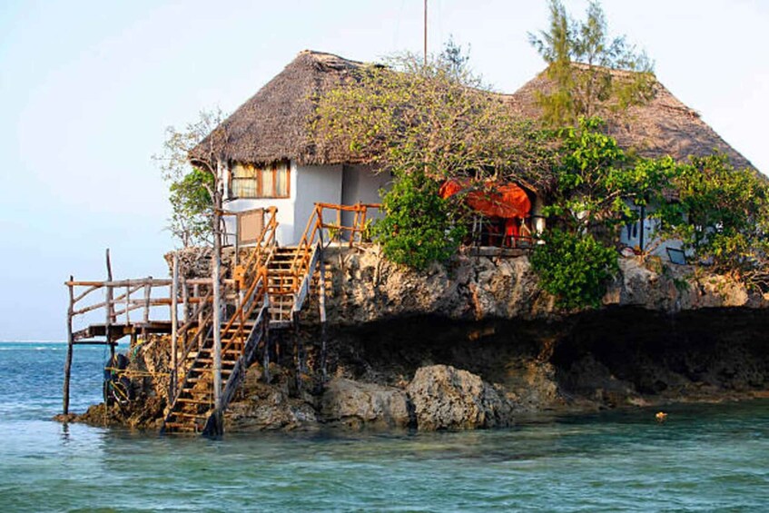 A house with a thatched roof on a rocky cliff by the sea. 4