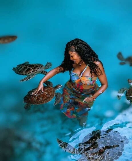 A person with sea turtles in a pool. 1