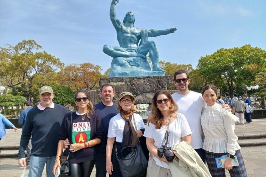 A group of people posing in front of a statue of a seated figure. 1