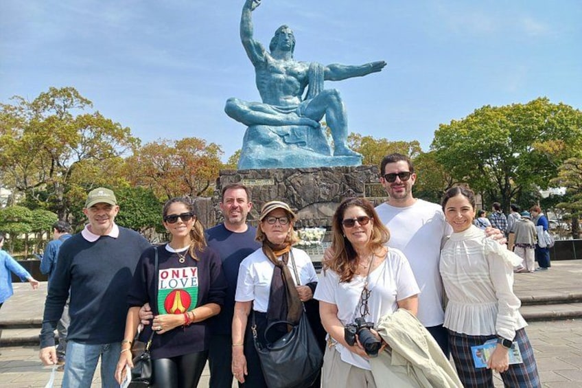 A group of people posing in front of a sculpture of a seated figure. 1