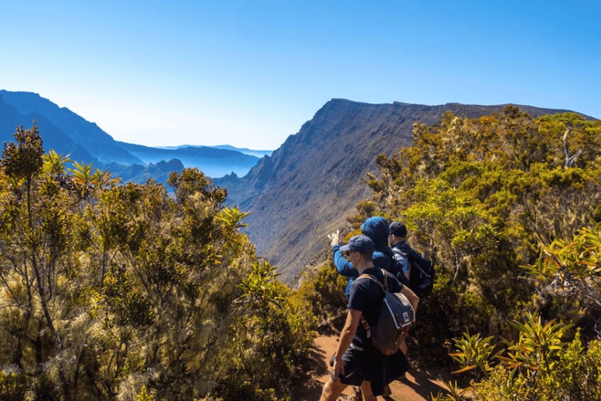 Hikers on a mountain trail with a view of a valley and distant mountains. 2