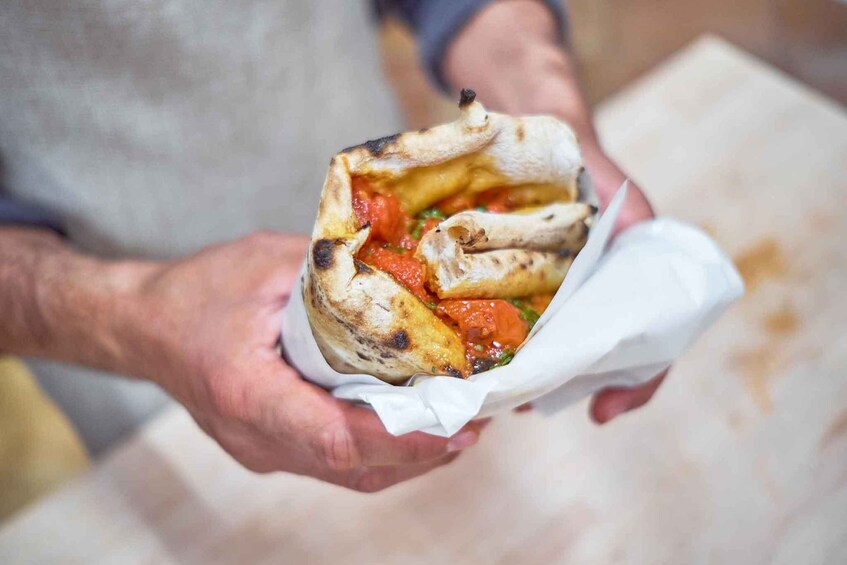 A person holding a pita sandwich with visible fillings. 5