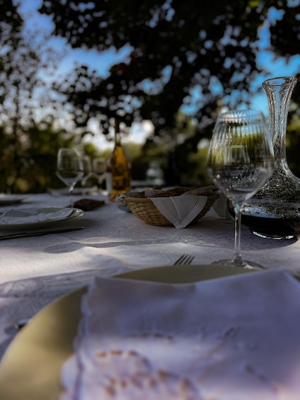 An outdoor dining table with a wine glass, a bottle, and a basket. 5