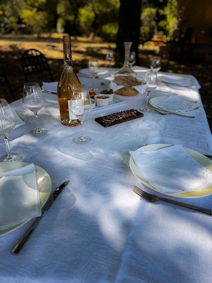 An outdoor dining table set with wine glasses, plates, and a bottle. 4