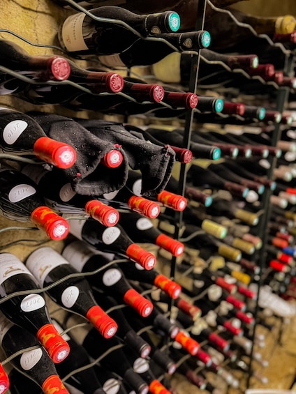 A collection of wine bottles with red and green caps, arranged on a rack. 3