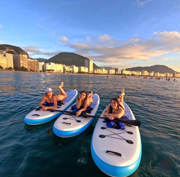 Three people on paddleboards in a body of water with a cityscape in the background. 2